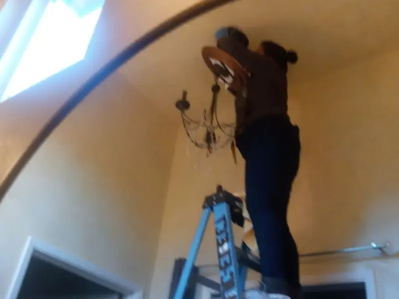 Electrician installing a chandelier in a Groves residence